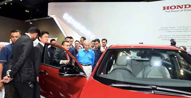 TERTARIK: Dr Mahathir (tiga kanan) mendengar penerangan daripada Naib Presiden (Pembuatan) Honda Malaysia Sdn Bhd Roslan Abdullah (empat kiri) ketika melawat Pameran Motor Antarabangsa Kuala Lumpur 2018 (KLIMS’18) di Pusat Dagangan dan Pameran Antarabangsa Malaysia (MITEC) di Kuala Lumpur, semalam. — Gambar Bernama