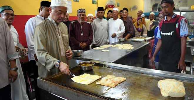 TUNJUK BAKAT: Sultan Abdullah menunjukkan bakat memasak roti canai ketika bersarapan bersama rakyat di sebuah restoran selepas menunaikan solat Subuh di Masjid Ash Shafie, Kotasas, dekat Kuantan, semalam. — Gambar Bernama