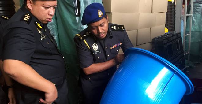 OPERASI MENGEJUT: Azeem (kanan) memeriksa saiz dan harga tong air ketika operasi mengejut             di sebuah kilang tong plastik di Kepong, Kuala Lumpur semalam. — Gambar Bernama