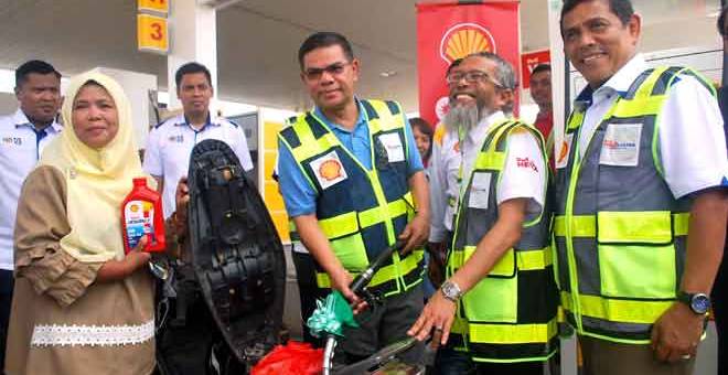 HARGA KAWALAN: Saifuddin (tiga kanan) mengisi petrol ke dalam tangki motosikal seorang penunggang secara percuma pada Program Perasmian Kempen Kesedaran Keselamatan Petroleum Peringkat Negeri Kedah semalam. — Gambar Bernama