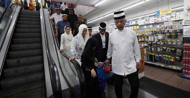 PRIHATIN: Al-Sultan Abdullah Ri’ayatuddin menarik sendiri troli yang sarat dengan pakaian raya anak-anak yatim ketika mencemar duli menemani kanak-kanak untuk membeli kelengkapan Aidilfitri di sebuah pasar raya di Kuantan semalam. — Gambar Bernama