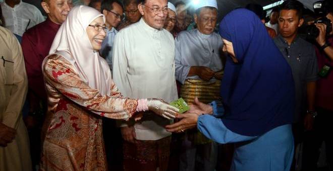 Timbalan Perdana Menteri Datuk Seri Dr Wan Azizah Wan Ismail (kiri) menyampaikan sumbangan kepada para penerima pada Jamuan Hari Raya Perdana Masjid Kubang Semang  dan turut kelihatan Anwar (dua kiri). - Gambar Bernama