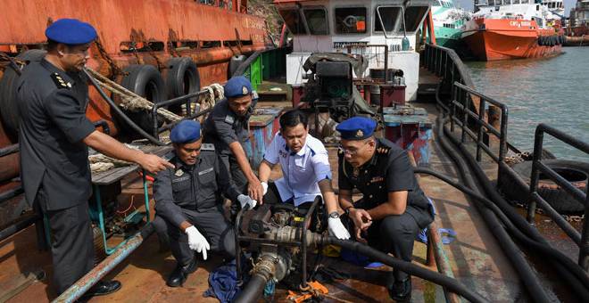 DISERBU: Saharuddin (dua kanan) bersama anggotanya memeriksa kapal yang membawa 104,200 liter minyak diesel secara haram di Jeti Sungai Kuang dekat Kemaman, semalam. — Gambar Bernama