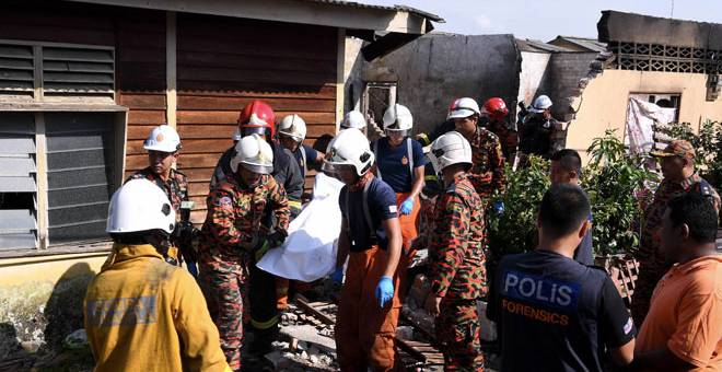 MAYAT RENTUNG: Anggota bomba dan penyelamat mengusung mayat mangsa warga Indonesia yang rentung dalam kebakaran di Jalan Sungai Udang, Klang, semalam.  — Gambar Bernama