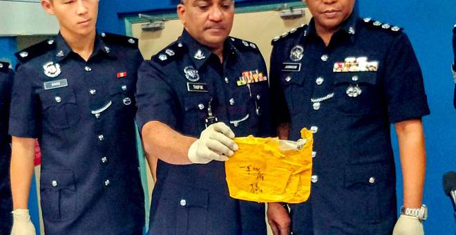 PENGEDARAN DADAH: Mohd Taufik (kari) menunjukkan plastik kuning yang mengandungi pil WY pada sidang akhbar di Ibu Pejabat Polis Daerah (IPD) Gua Musang, semalam. — Gambar Bernama