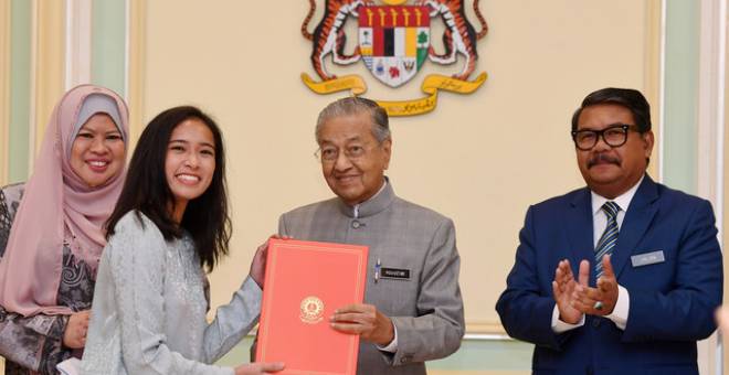 Dr Mahathir (dua, kanan) menyampaikan surat tawaran kepada Wan Farisa Alia Wan Mohd Fadzmi (dua, kiri) pada Majlis Penyampaian Surat Tawaran Pinjaman Pelajaran Bagi Pelajar MARA di Perdana Putra hari ini. Turut sama Menteri Pembangunan Luar Bandar Datuk Seri Rina Mohd Harun (kiri) dan Ketua Setiausaha Pembangunan Luar Bandar Datuk Dr Ahmad Jailani Mohamed Yunus (kanan). - Gambar Bernama 