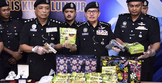 DIRAMPAS: Mazlan (dua kanan) menunjukkan dadah dan senjata api yang dirampas ketika sidang media di Ibu Pejabat Polis Kontinjen Kuala Lumpur semalam.— Gambar Bernama