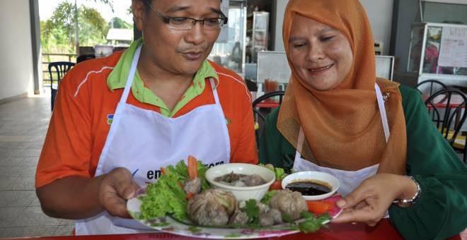 IDEA KREATIF: Helmy (kiri) bersama isterinya Rosmawati menunjukkan bakso citarasa durian yang direkanya dari cetusan idea kreatif di gerainya di Pasar Tani Kekal (PTK) Nyiur Tujuh bagi memenuhi selera peminat durian seiring dengan musim durian sekarang di Jertih, semalam. — Gambar Bernama