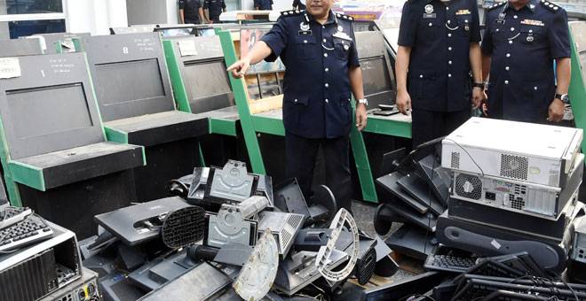 DILUPUS: Mohd Said (kiri) bersama pegawainya menunjukkan barangan yang akan dilupuskan pada majlis pelupusan barang kes mesin perjudian siber di Stor Barang Kes Berpusat, Sikamat dekat Seremban, semalam. — Gambar Bernama