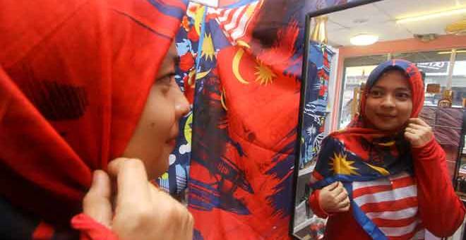 CORAK PATRIOTIK: Asrizawani menggayakan tudung bercorak patriotik dengan gabungan warna Jalur Gemilang yang dijual di kedainya ketika tinjauan Bernama di Kangar, kelmarin. — Gambar Bernama