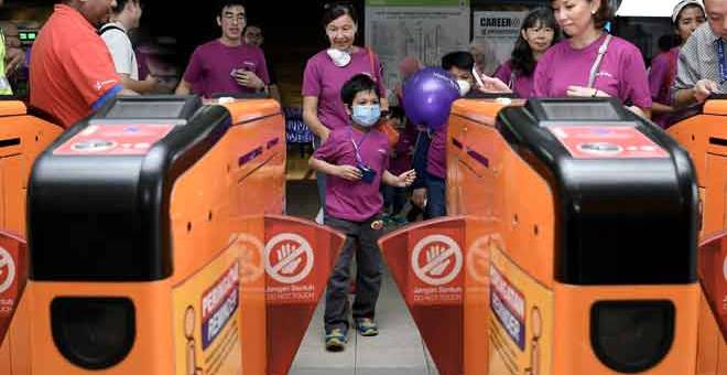 GEMBIRA: Pesakit leukemia Ahmad Wazif memasuki terminal monorel Imbi sempena meraikannya dengan menaiki Transit Aliran Massa (MRT)/Transit Aliran Ringan (LRT) di Kuala Lumpur, semalam. — Gambar Bernama