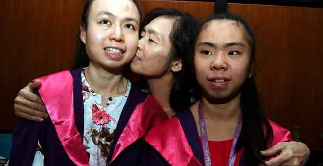 TAHNIAH: Teresa Wong mencium Felicia yang akan menerima pingat emas Universiti Sains Malaysia (USM) bagi pelajar kelainan upaya pada Majlis Konvokesyen USM ke-57 yang bermula esok pada sidang akhbar semalam. — Gambar Benama