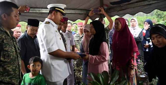 SUASANA PILU: Siti Salbiah Roslie, balu kepada Mohamad Ikmal, menerima Jalur Gemilang sebaik jenazah suaminya selamat dikebumikan di Tanah Perkuburan Islam Bukit Rangin semalam.  — Gambar Bernama