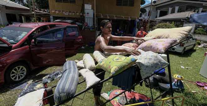 SIBUK: Mangsa banjir, Muzammir Hussien, 40, menjemur bantal ketika membersihkan kediamannya selepas banjir surut di Kampung Sungai Rokam semalam. — Gambar Bernama