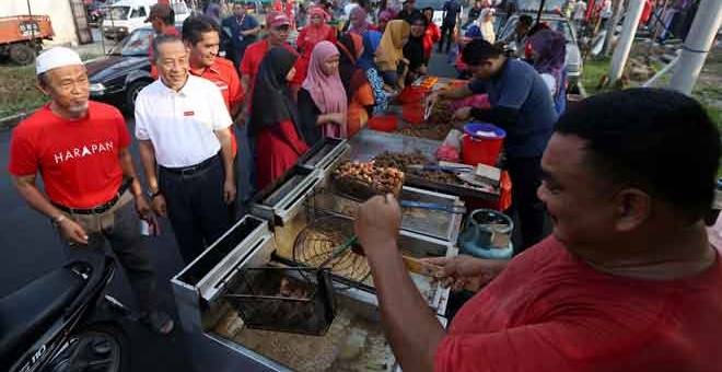 LAWAT: Karmaine (dua kiri) bersama Timbalan Menteri Hal Ehwal Ekonomi Dr Mohd Radzi Md Jidin (tiga kiri) beramah mesra dengan para peniaga Pasar Pagi Pekan Serkat Laut pada kempen PRK Parlimen Tanjung Piai dekat Pontian, semalam. — Gambar Bernama