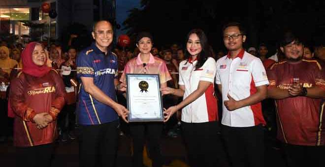 CIPTA REKOD: Tengku Permaisuri Norashikin (tengah) berkenan menyaksikan penyerahan sijil Malaysia Book of Records sebagai ‘The Largest Participation In A Songket Running Event’ daripada wakil Malaysia Book of Records.