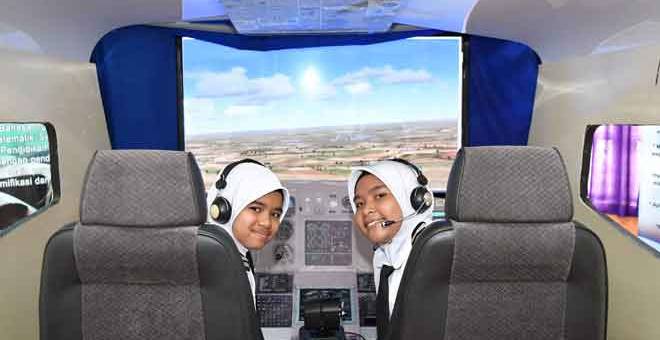 MENGGAPAI  CITA-CITA:  ‘Kapten’ Nur Alya Damia (kanan) dan ‘Kapten’ Atiqah Yasmin Zuyawi, 12, antara pelajar yang mahir mengendalikan simulator pesawat milik sekolah yang dibina daripada barangan terpakai ketika ditemui di Marang, semalam. — Gambar Bernama