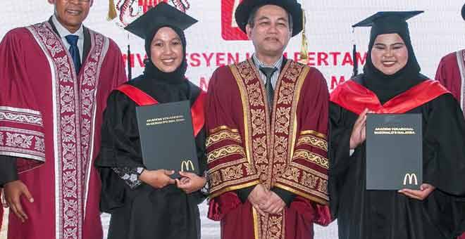 TAHNIAH: Azmir Jaafar (kiri), Ketua Setiausaha, Kementerian Sumber Manusia Malaysia, Datuk Amir Omar (tengah), bergambar mesra bersama penerima-penerima Anugerah Graduan Cemerlang Program Perantis Vokasional McDonald’s Noor Fazriza Fazlin Abdul Rahim dan Nuraizah Hamdiin (kanan) yang memakai jubah hitam.