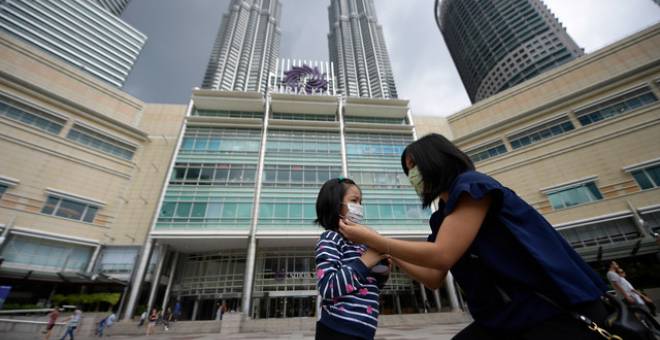  Seorang pelancong wanita memakaikan topeng muka kepada anak perempuannya dengan berlatar belakangkan suasana lengang di sekitar taman rekreasi Suria KLCC walaupun pada hari minggu susulan penularan COVID-19 ketika tinjauan di sekitar ibu kota baru-baru ini. - Gambar Bernama 