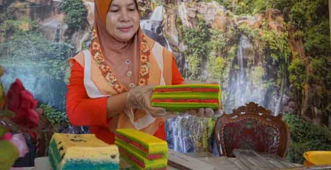 BANYAK TEMPAHAN: Rajemah Rose Awi menunjukkan kek lapis masam manis yang ditempah pelanggan ketika tinjauan di rumahnya di Kampung Bubor, semalam. — Gambar Bernama