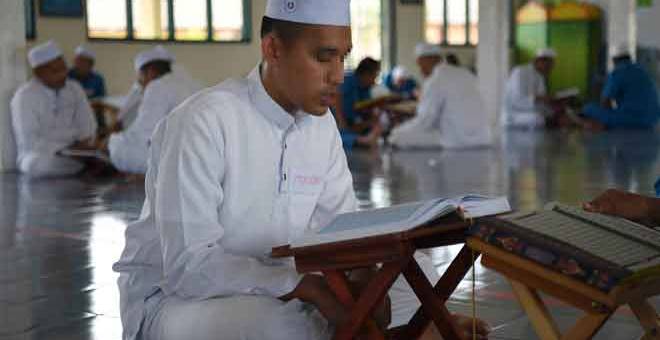 RUTIN: Banduan Penjara Marang yang mahu dikenali sebagai Azizul bertadarus Al-Quran ketika tinjauan baru-baru ini. — Gambar Bernama