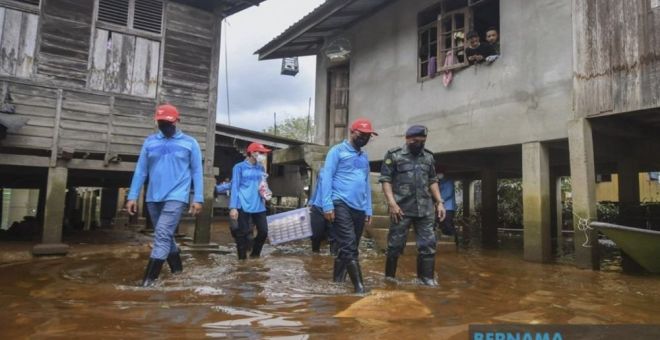 Pengarah Urusan Al Tamim World Sdn Bhd, Datuk Ku Ardanan Dollah (dua, kanan) bersama Pegawai Pemerintah Pasukan Gerakan Am (PGA7) Supt Azhari Nusi (kanan) meredah air sewaktu menyampaikan sumbangan bantuan kepada sebahagian mangsa banjir di Kampung Tersang, Rantau Panjang hari ini. -Gambar Bernama