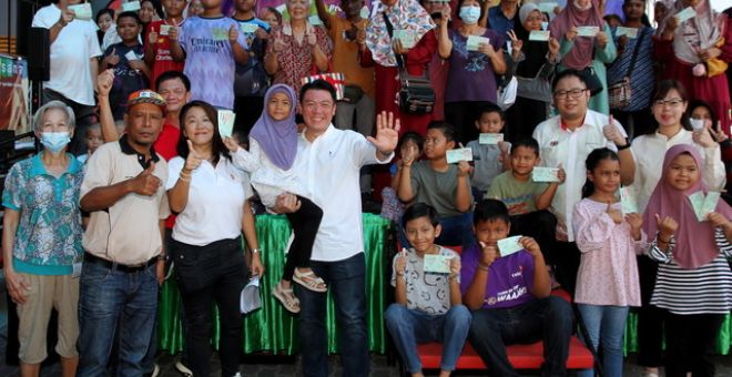 Nga (lima, kiri) bergambar kenangan bersama penerima bantuan baucer Hari Raya pada Program Meriah Beraya di sebuah pusat beli-belah di sini hari ini.-Gambar BERNAMA