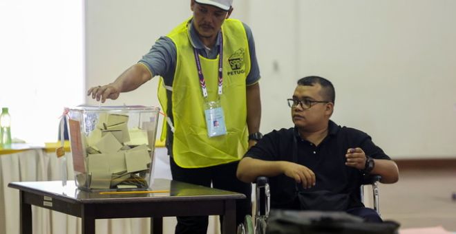 Anggota polis yang sakit dibantu oleh pegawai SPR ketika menjalankan tanggungjawab mereka dengan mengundi awal sempena Pilihan Raya Kecil N.06 Kuala Kubu Baharu di Maktab Polis Diraja Malaysia PDRM Kuala Kubu Baharu hari ini. - Gambar BERNAMA