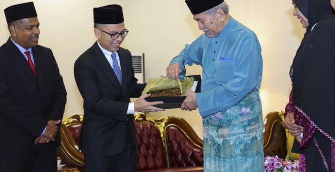 Tun Wan Junaidi (dua, kanan) menerima cenderamata daripada Fahmi (dua, kiri) di Astana Negeri di Petra Jaya hari ini. - Gambar BERNAMA