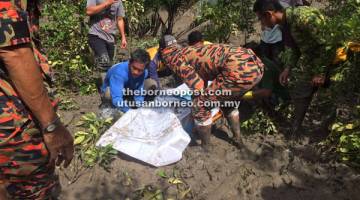 MENYAYAT HATI: Anggota penyelamat dibantu penduduk kampung mengangkat mayat mangsa dari lokasi penemuan untuk dihantar ke HUS.