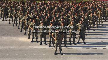 TEGUH: Fadzil (tengah) merakam kenangan bersama pegawai dan anggota Briged Ke-31 Infantri selepas Perbarisan Pembacaan Perintah Ulung Panglima Tentera Darat dan Perintah Ulung Panglima Briged Ke-31 Infantri di Kem Junaco Park di Sibu, semalam.