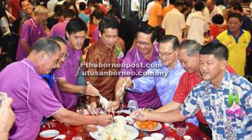 MAKMUR: Dennis (tengah) bersama tetamu kenamaan di meja utama, menyempurakan acara ‘Yee Sang’. 