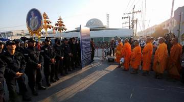 KEPUNG: Anggota polis menyekat sami Buddha di hadapan pagar masuk ke Wat Dhammakaya di wilayah Pathum Thani, utara Thailand semalam. — Gambar Reuters