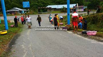 BERAT SAMA DIPIKUL: Penduduk kampung membersihkan kawasan gerbang pintu masuk ke kampung itu.