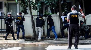 KEGANASAN: Gambar serahan Antara Foto menunjukkan beberapa anggota polis mengawal keadaan berhampiran pejabat kerajaan tempatan susulan letupan bom di Bandung, Jawa Barat semalam. — Gambar Reuters
