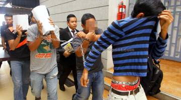 KE MUKA PENGADILAN: Empat lelaki diiringi anggota polis untuk didakwa di Mahkamah Sesyen Kangar semalam berhubung kes memiliki senjata api. — Gambar Bernama