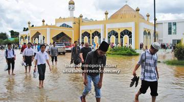 TUNAI TANGGUNGJAWAB: Jemaah selesai menunaikan solat Jumaat menyinsing seluar ke paras betis apabila pekarangan Masjid An-Nur dinaiki air.