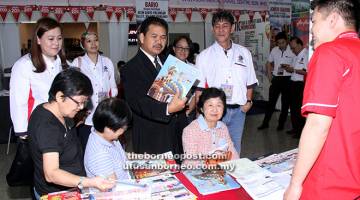 LANCAR: Ik Pahon (tengah) kelihatan membaca risalah tawaran pakej pelancongan selepas melancarkan Pameran MATTA Ke-10 di Pusat Beli-Belah Boulevard, Kuching semalam.