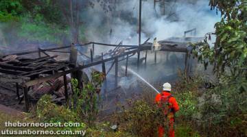 PADAM: Anggota bomba memadamkan kebakaran rumah kayu di Limbang semalam.