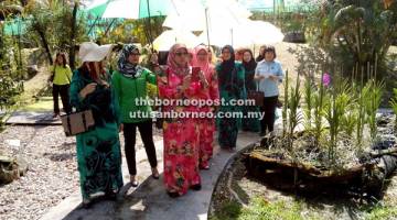 MINAT ORKID: Dayang Asmah mengambil gambar salah satu bunga orkid kesukaan beliau sewaktu menyertai lawatan ke DBKU Orchid Park bersama ahli BISTARI semalam.