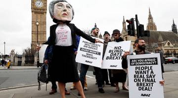 PROTES: Pembantah Brexit, memakai kepala gergasi Theresa May, memegang plakad di luar Parlimen pada hari perdana menteri mengumumkan beliau secara rasmi memulakan prosedur untuk memisahkan Britain dari EU di London, kelmarin. — Gambar Reuters