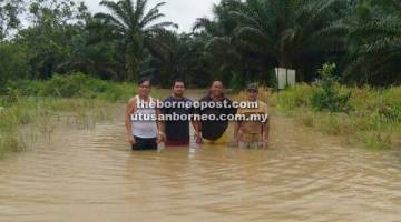 DALAM: Penduduk menunjukkan kedalaman air yang menenggelamkan jalan utama masuk ke kawasan rumah panjang di Subis, Niah. 