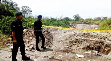 TAK BOLEH MASUK: Dua anggota polis mengawal laluan masuk ke lokasi sayap ayam ditimbus. — Gambar Bernama