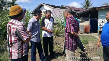 TINJAU: Naroden (dua kiri) kelihatan berbual bersama Adri ketika lawatannya ke tapak rumah yang rosak akibat hakisan tebing sungai di Kampung Ensengei Melayu, di Sadong Jaya, semalam.