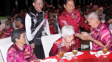 PRIHATIN: Wong menyampaikan angpau kepada warga emas dari Hun Nam Siang Tng yang dijemput khas pada majlis makan malam Sambutan Hari Ibu Bapa UPP di KTS Garden, kelmarin. Turut kelihatan Lo (kiri).