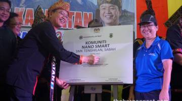 TEKNOLOGI TERKINI: Madius (kiri) menandatangani plak Komuniti Nano Smart SMK Tenghilan sambil disaksikan oleh salah seorang warga pendidik di sekolah berkenaan.