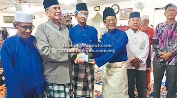 KENANGAN: Wakil Masjid Darul Iman menyampaikan cenderamata kenang-kenangan kepada Wan Junaidi (dua kiri) pada Majlis Penyampaian Sumbangan Kebajikan Bagi Zon Jalan Bako di Kuching, malam kelmarin.