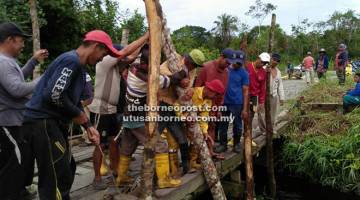 KERJASAMA: Penduduk Kampung Kupang bekerjasama membaiki jambatan merentasi Sungai Sedan memastikan penduduk dapat melaluinya. 