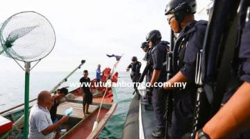 Sepasukan anggota APMM bersedia untuk memeriksa bot nelayan tempatan yang ditahan dalam rondaan di perairan Kuching semalam.
