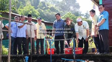 AIR BERSIH: Wan Junaidi (empat kanan) dan Dr Rahman (lima kanan) membuka pili air sebagai simbolik prapelancaran projek BALB di Kampung Pulau Salak semalam.